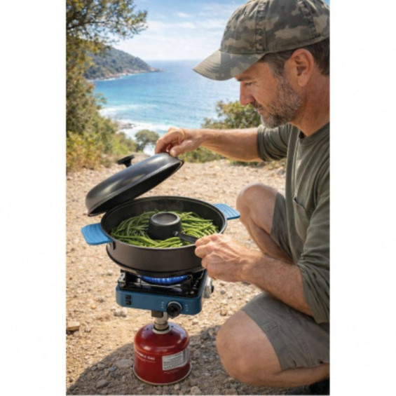 Homme en tenue de camouflage et casquette utilisant le four nomade TANDOOR sur un réchaud à gaz de camping portable en extérieur