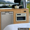 Réfrigérateur 65l noir Nomadic Ark installé dans un van aménagé avec habillage bois
