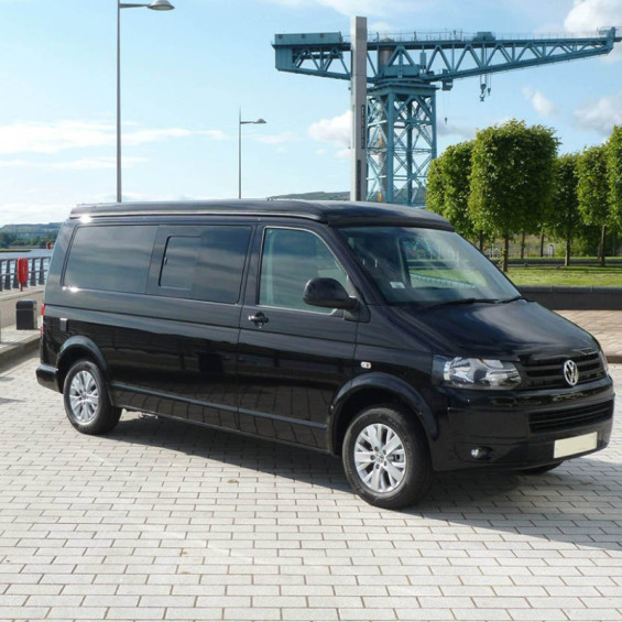 Volkswagen Transporter T5 noir avec fenêtre latérale coulissante, vue 3/4 avant sur un quai portuaire