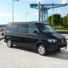 Volkswagen Transporter T5 noir avec fenêtre latérale coulissante, vue 3/4 avant sur un quai portuaire