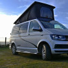 Volkswagen California gris, toit relevable ouvert, fenêtre coulissante avant droite, vue 3/4 avant